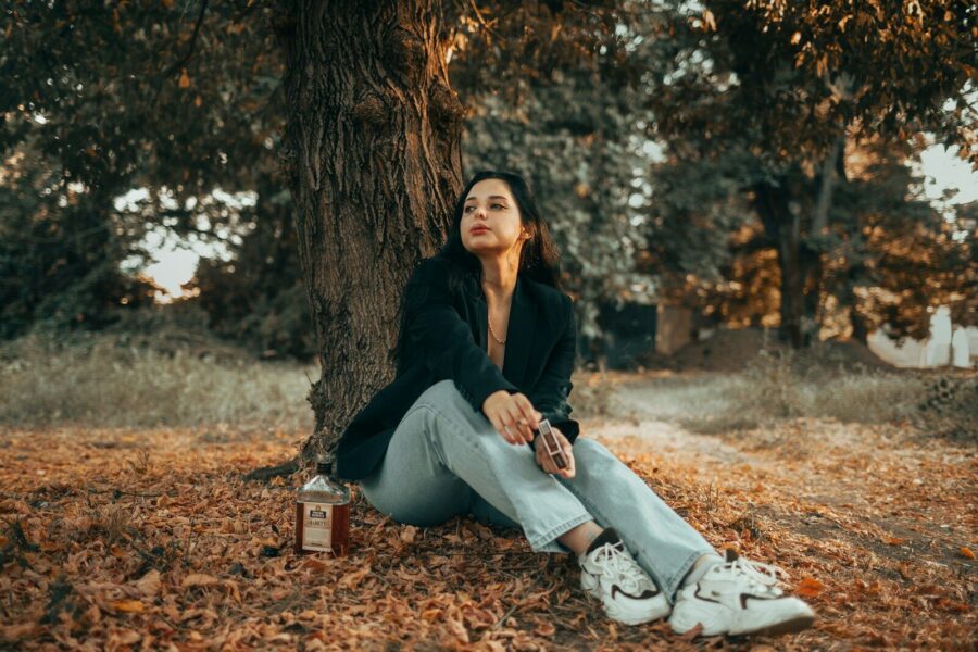 woman sitting under a tree, contemplating alcohol detox timelines