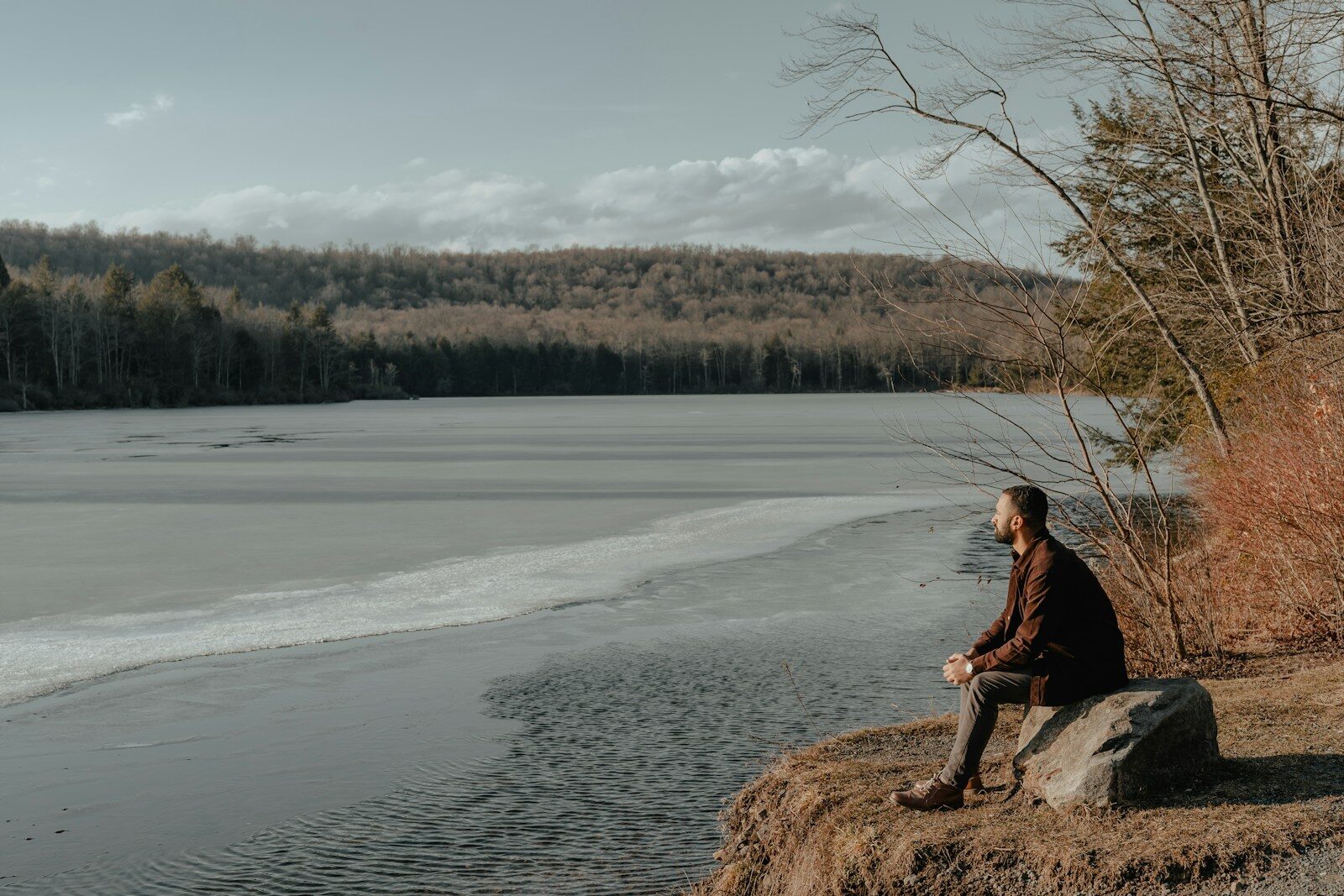 A man thinking about alcohol consumption effects on the body on a rock next to a river