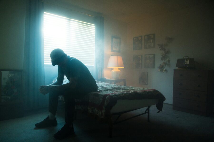 Man sitting on bed struggling with fight flight freeze fawn flop
