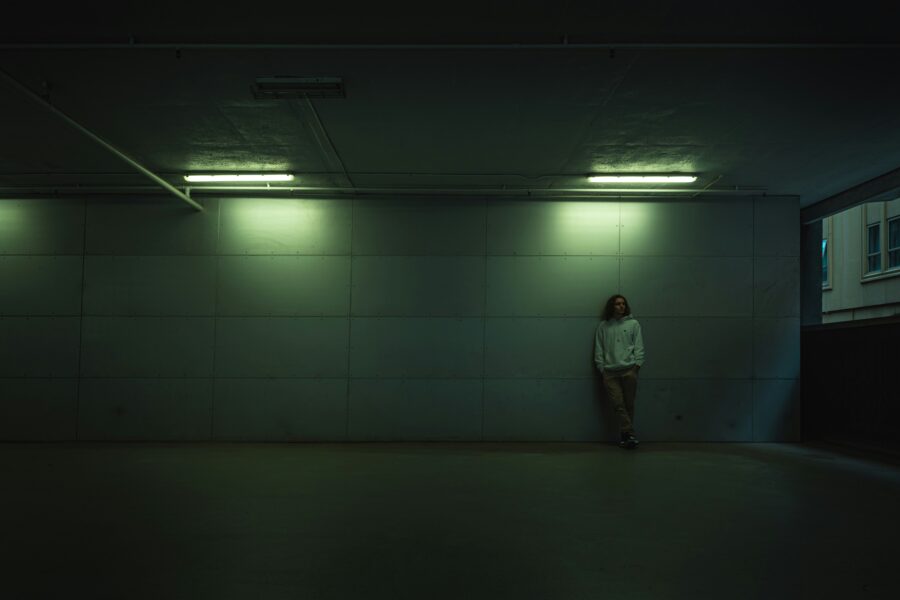 Man standing in a dark room struggling with schizophrenia and alcohol