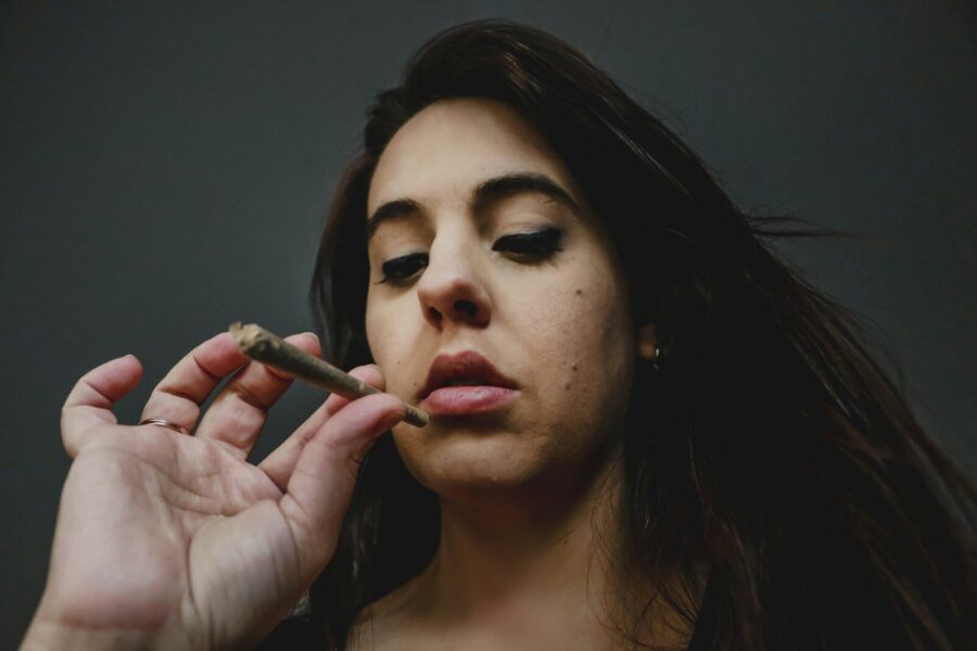 woman holding a joint wondering, "Is weed addiction real?" as she has second thoughts.
